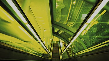 Neon yellow and lime green lights along a descending escalator