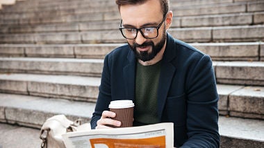 woman-asks-question-at-meeting Man sitting outside on stairs reading a newspaper