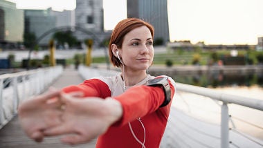 woman stopping to stretch on bridge after jogging