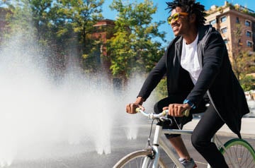 Handsome afro man riding a bike in the street.